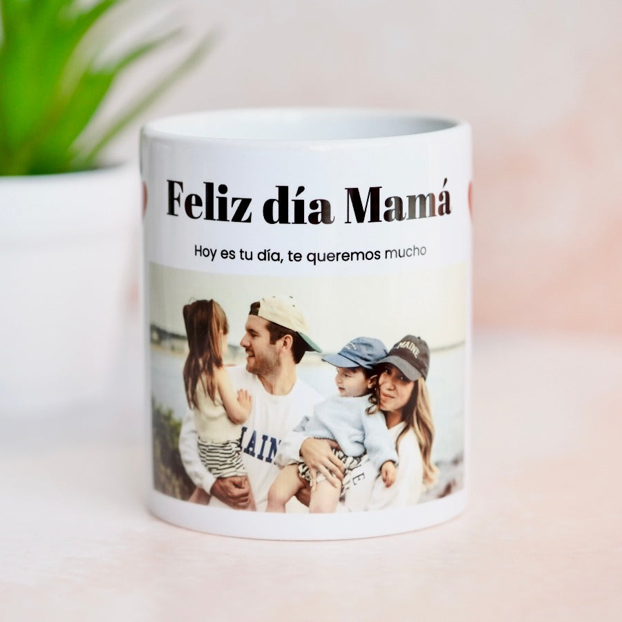Imagen de una taza blanca personalizada con una foto central, rodeada de dos corazones y una frase con la palabra 'MAMA' en la parte inferior.